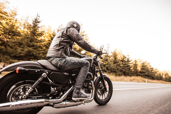 A man riding a motorcycle alone in the road