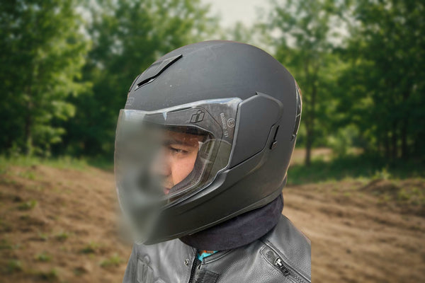 Rider wearing the GEARS soft foam neck collar under a full-face helmet on a wooded trail